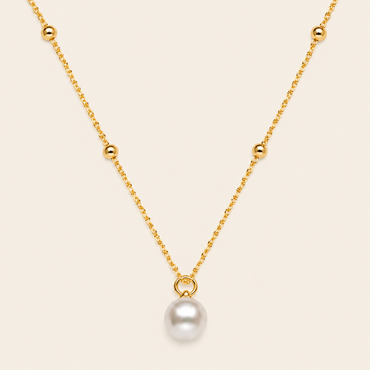 Gold necklace with a single pearl pendant on a beige background