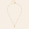 Gold necklace with a single pearl pendant on a beige background