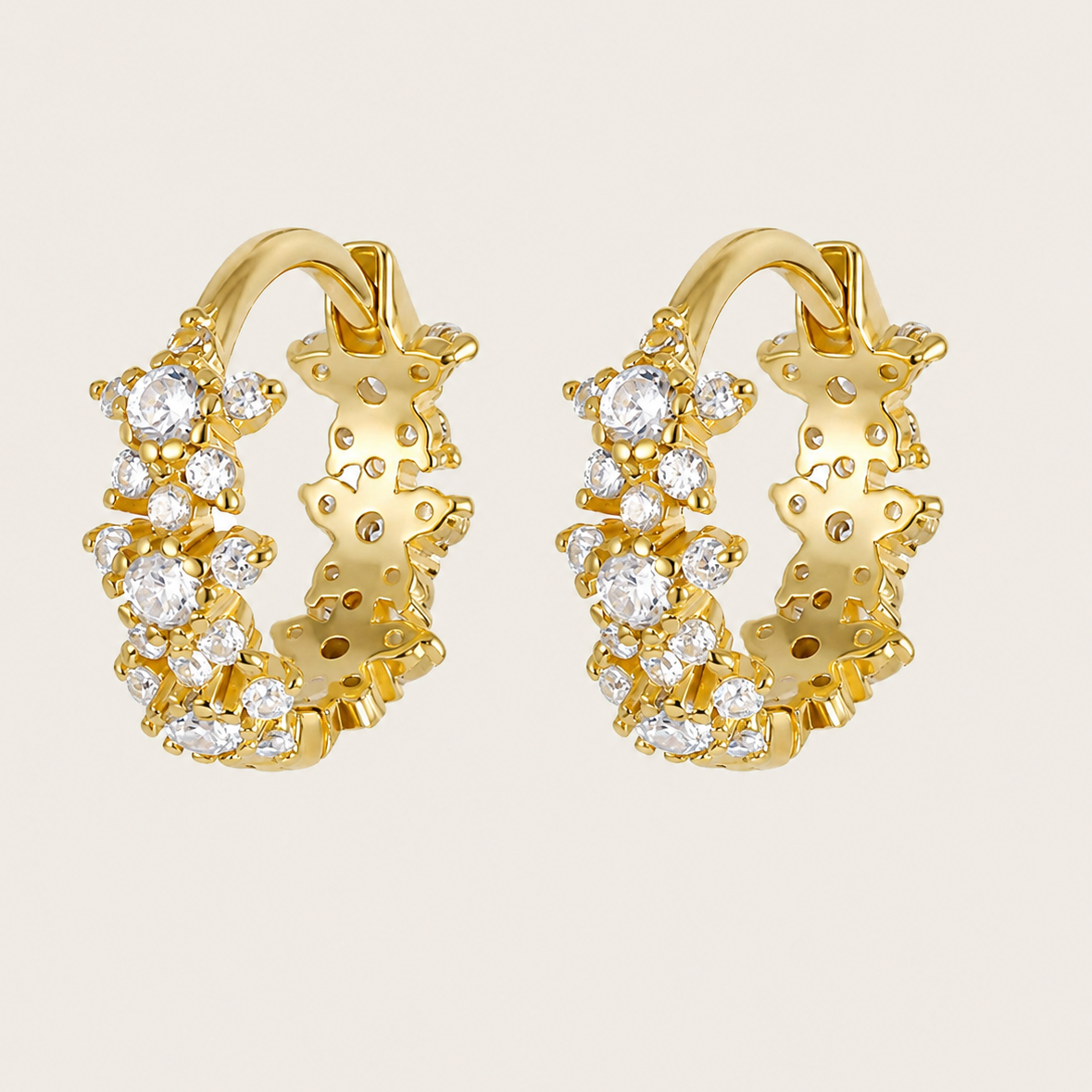 Gold hoop earrings with diamond accents on a beige background