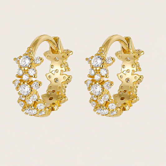 Gold hoop earrings with diamond accents on a beige background