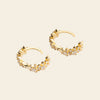 Gold hoop earrings with diamond accents on a beige background