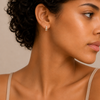 Close-up of a woman wearing diamond earrings with a neutral background