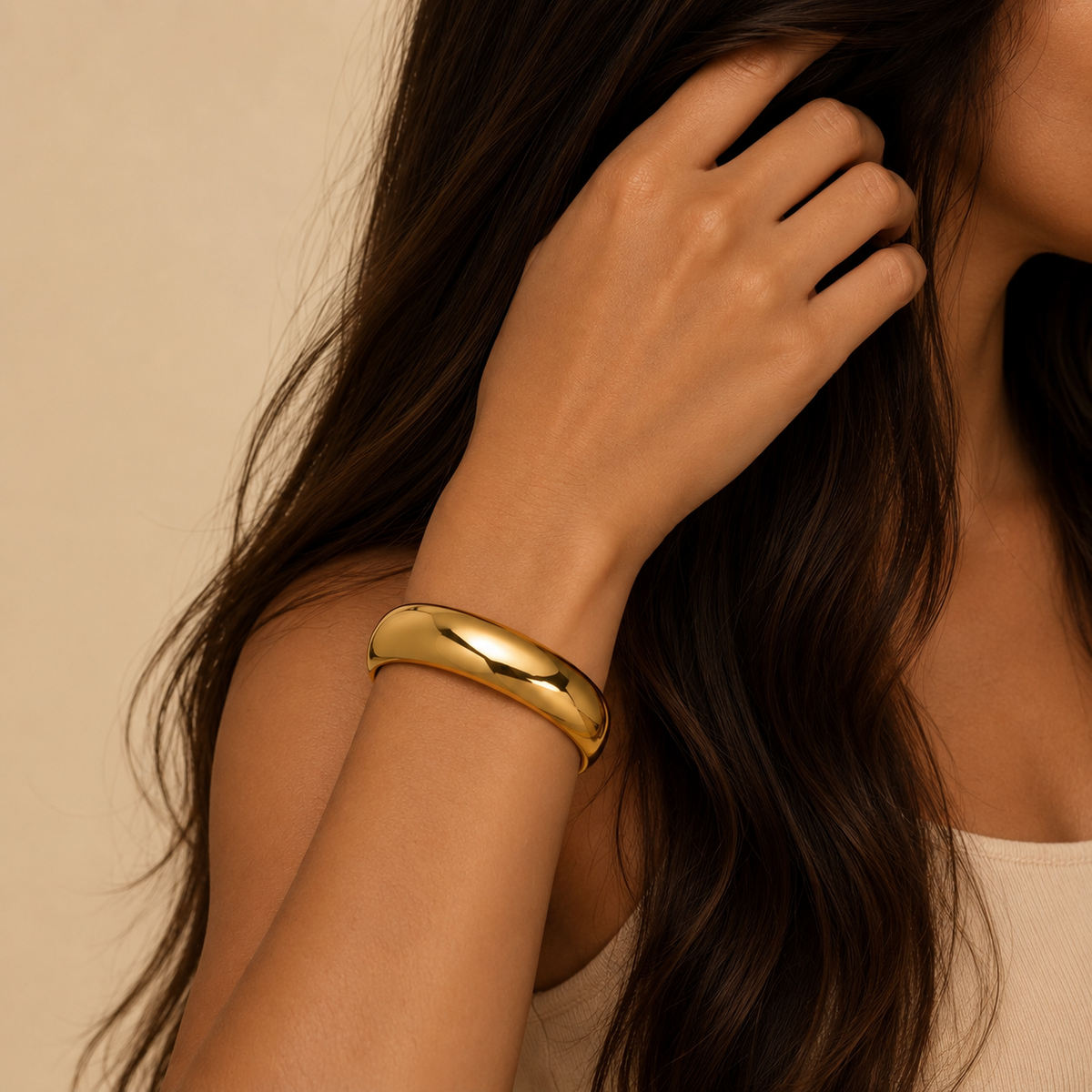 Woman wearing a gold bracelet with a neutral background