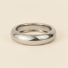 A polished silver band ring with a smooth, rounded profile, photographed on a clean, solid, warm off-white background.