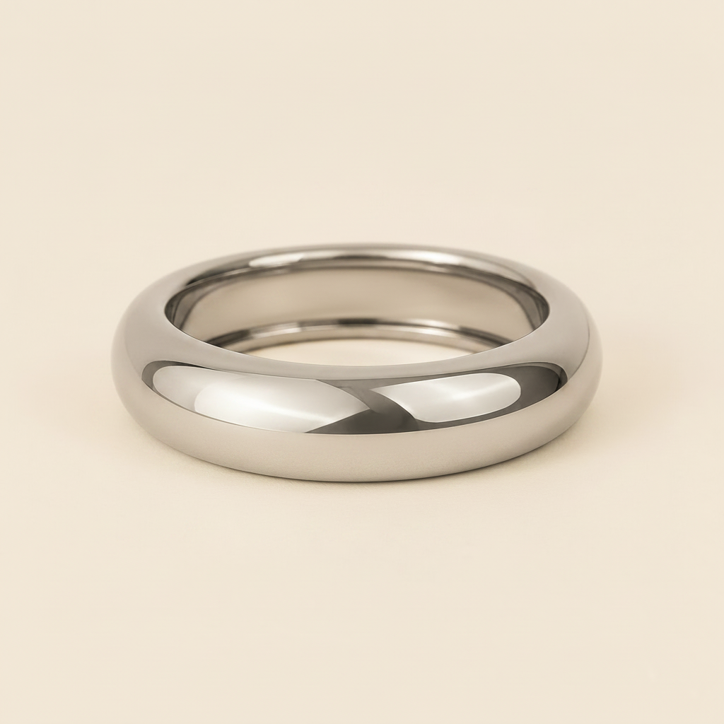 A polished silver band ring with a smooth, rounded profile, photographed on a clean, solid, warm off-white background.