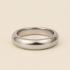 A polished silver band ring with a smooth, rounded profile, photographed on a clean, solid, warm off-white background.