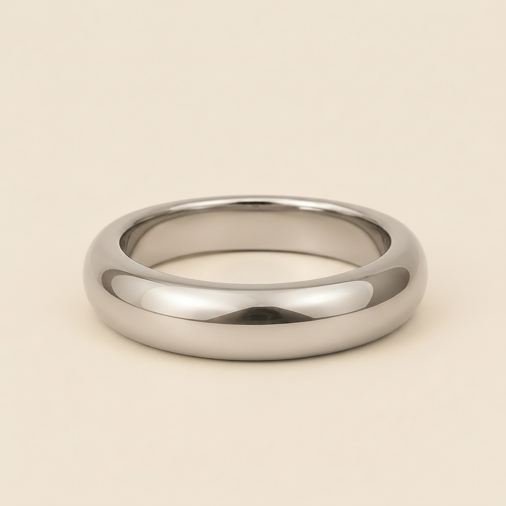 A polished silver band ring with a smooth, rounded profile, photographed on a clean, solid, warm off-white background.