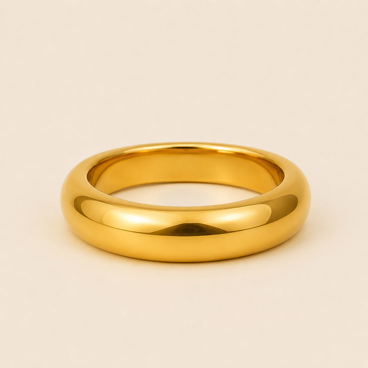 A polished yellow gold band ring with a smooth, rounded profile, photographed on a clean, solid, warm off-white background.