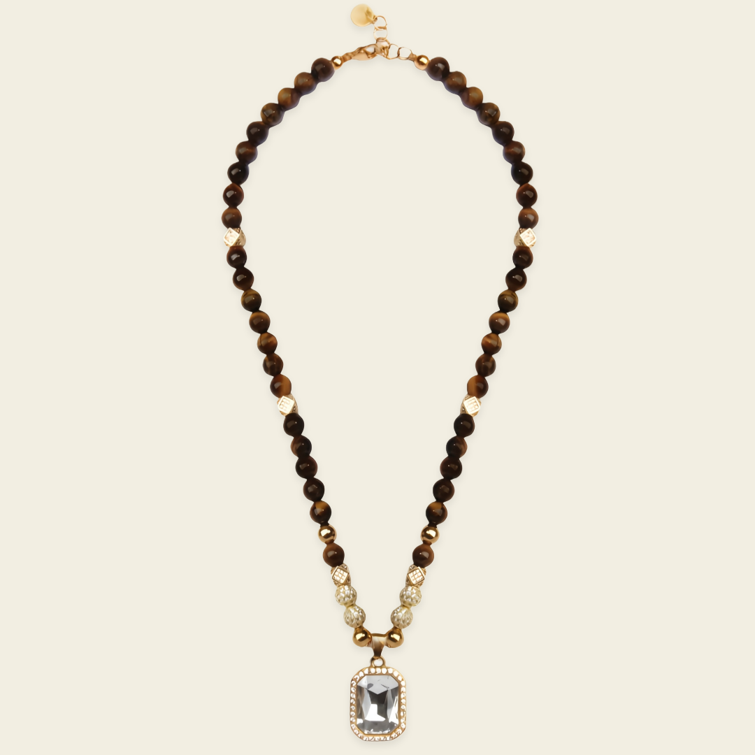 A beaded necklace featuring dark brown and black tiger's eye beads with small gold spacer beads, a gold-toned clasp, and a rectangular smoky gray stone pendant surrounded by a gold bezel.