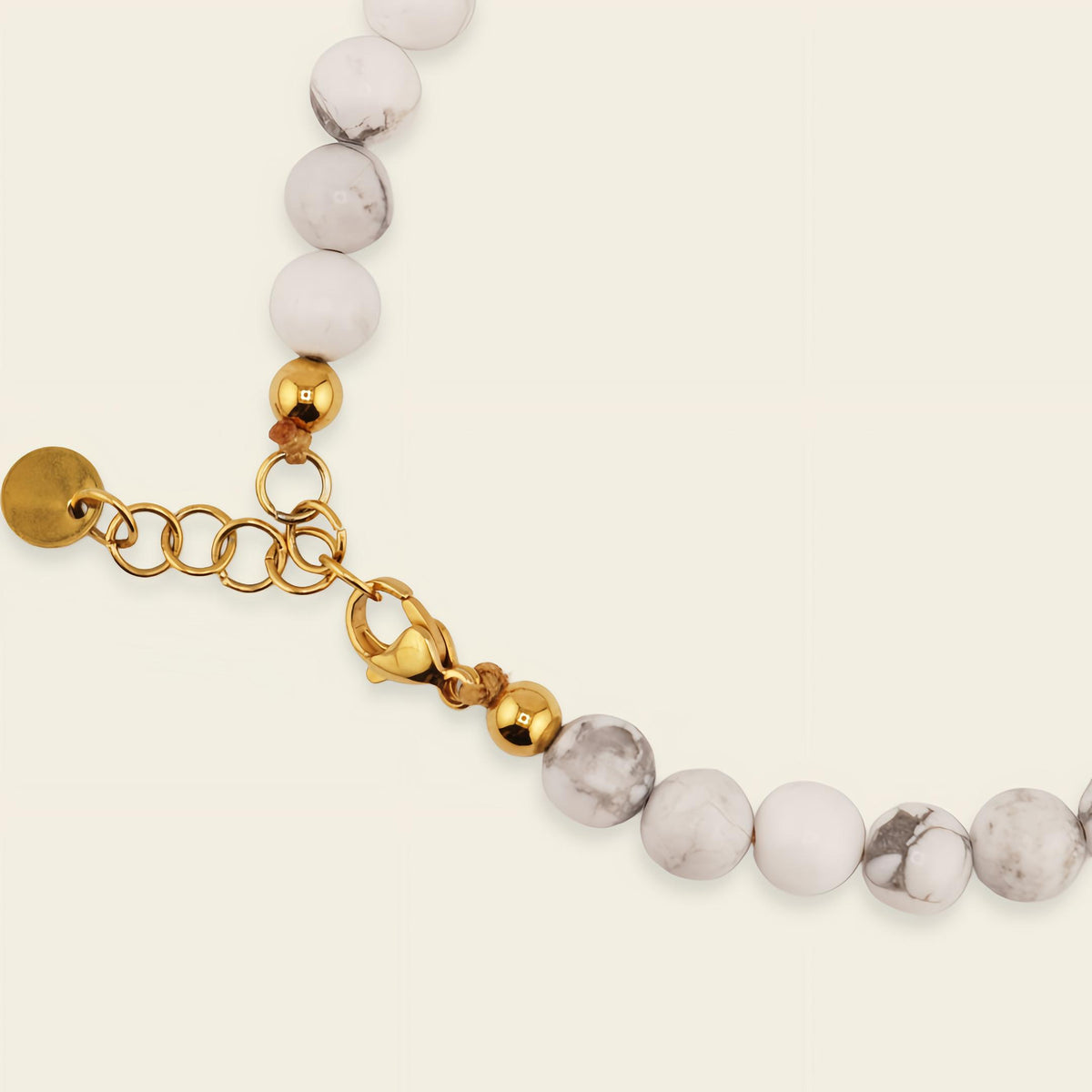Clasp with white beads and gold accents on a light beige background