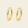 A pair of polished gold huggie hoop earrings on a warm cream background.