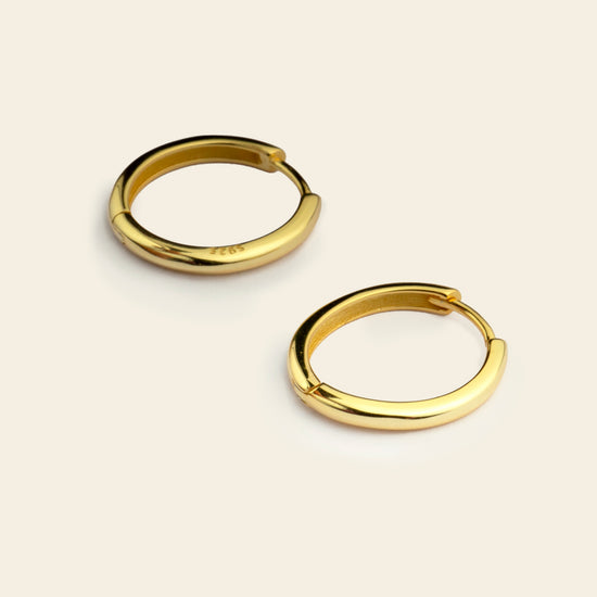 Gold hoop earrings on a beige background