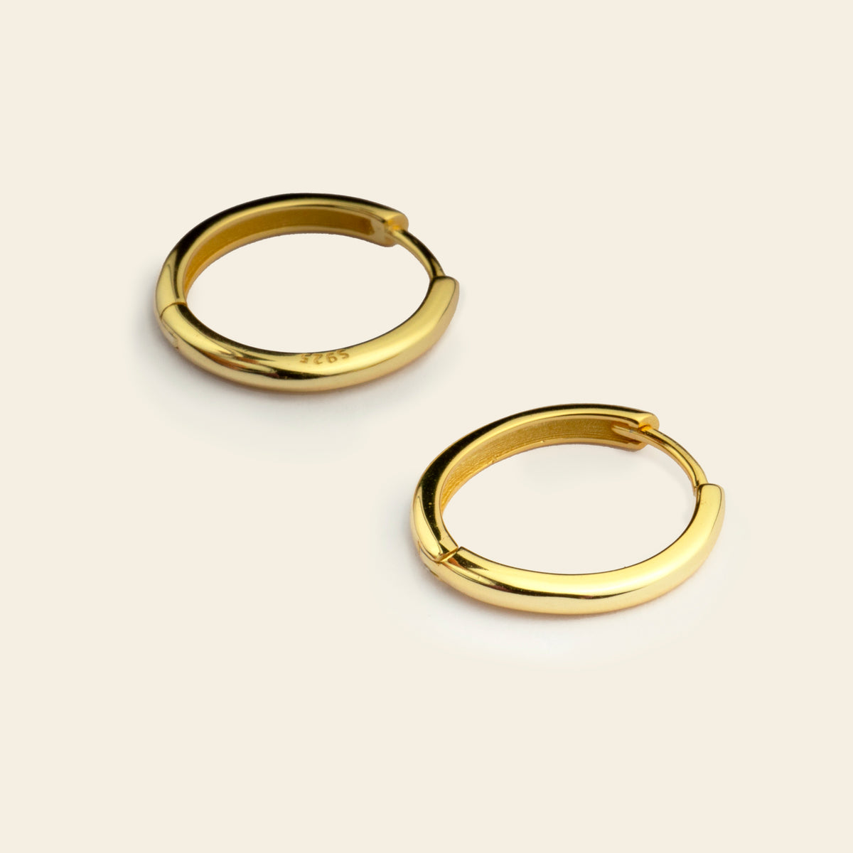 Gold hoop earrings on a beige background