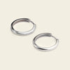 Pair of silver hoop earrings on a beige background