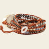 Multistrand bracelet with beads and leather wrap on a beige background
