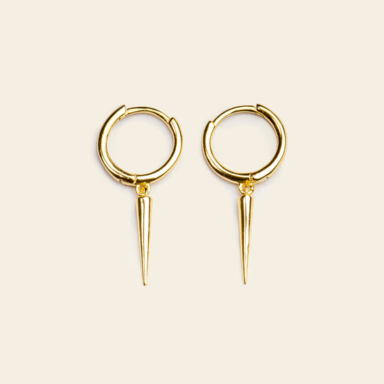 Gold hoop earrings with spike details on a beige background
