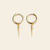 Gold hoop earrings with spike details on a beige background