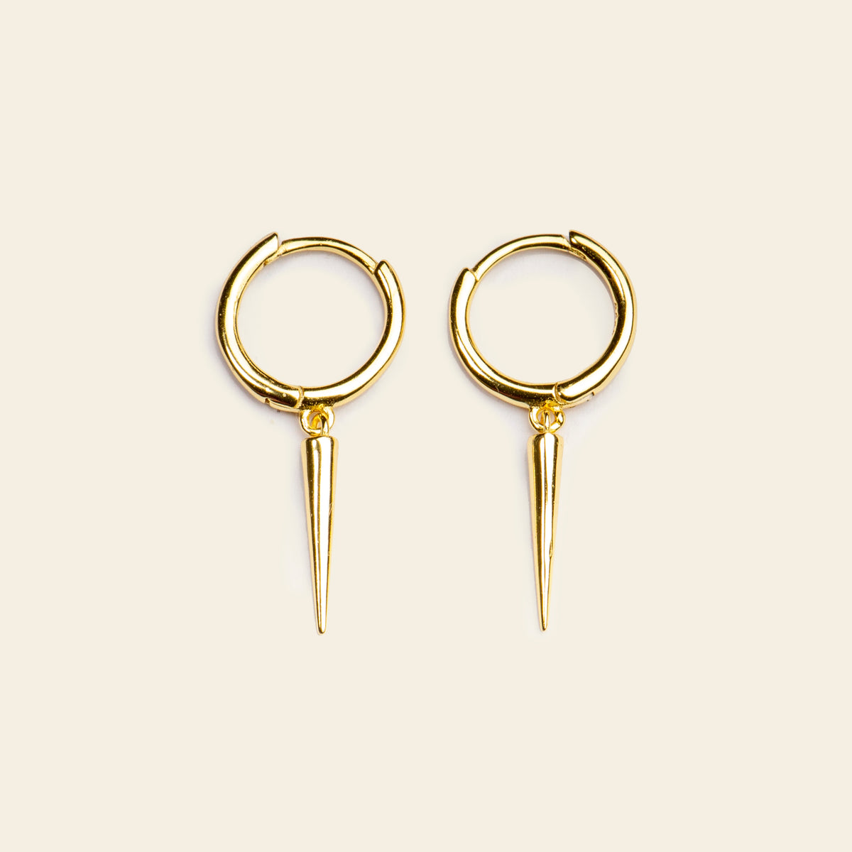 Gold hoop earrings with spike details on a beige background