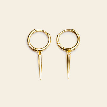 Gold hoop earrings with spike details on a beige background