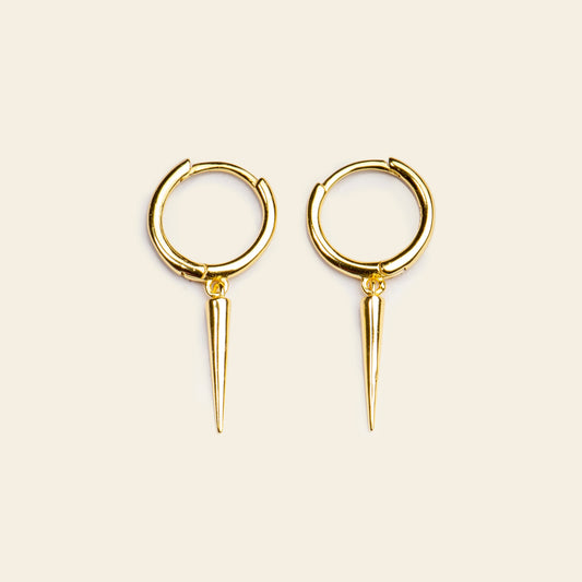 Gold hoop earrings with spike details on a beige background