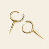 Gold hoop earrings with spike details on a beige background
