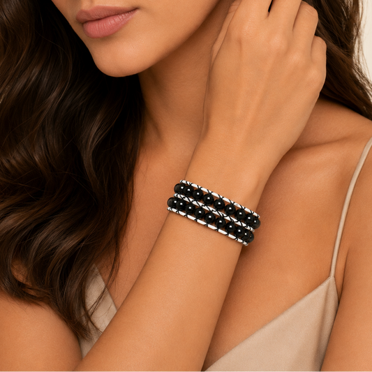 Woman wearing a black beaded bracelet on a neutral background