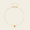 Gold bracelet with a heart charm on a beige background