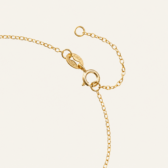 Gold bracelet with clasp on a light beige background