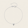 Silver bracelet with a heart-shaped charm on a beige background