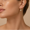 Close-up of a woman wearing a heart-shaped earring on a beige background