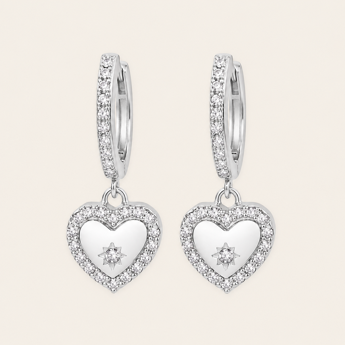Heart-shaped silver earrings with clear stones on a light gray background