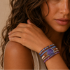 Close-up of a woman's arm with colorful bracelets on a neutral background
