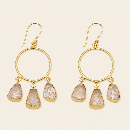 Gold hoop earrings with stone drops on a beige background