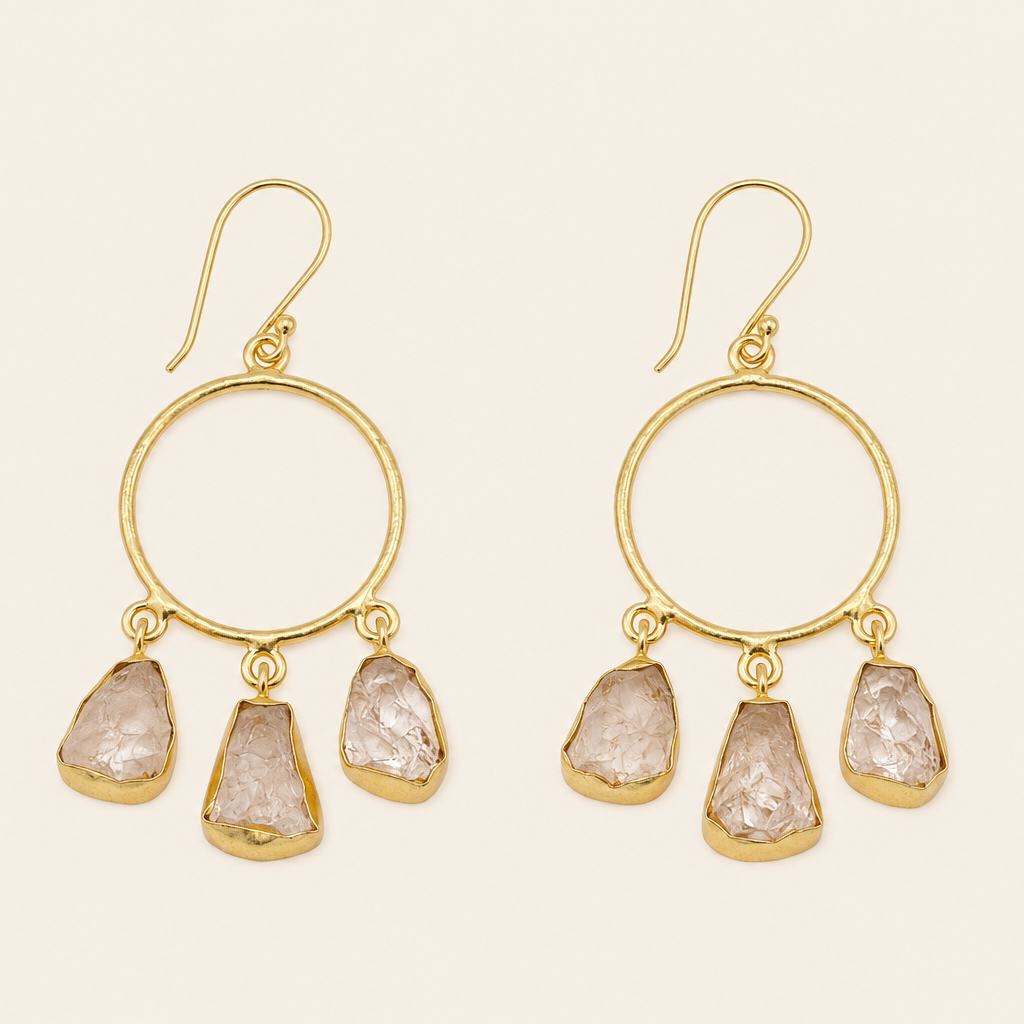 Gold hoop earrings with stone drops on a beige background