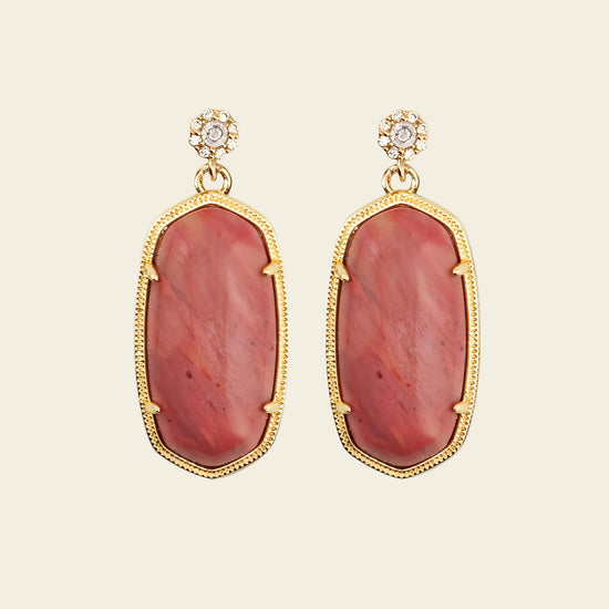 Pair of earrings with red stone and gold frame on a beige background