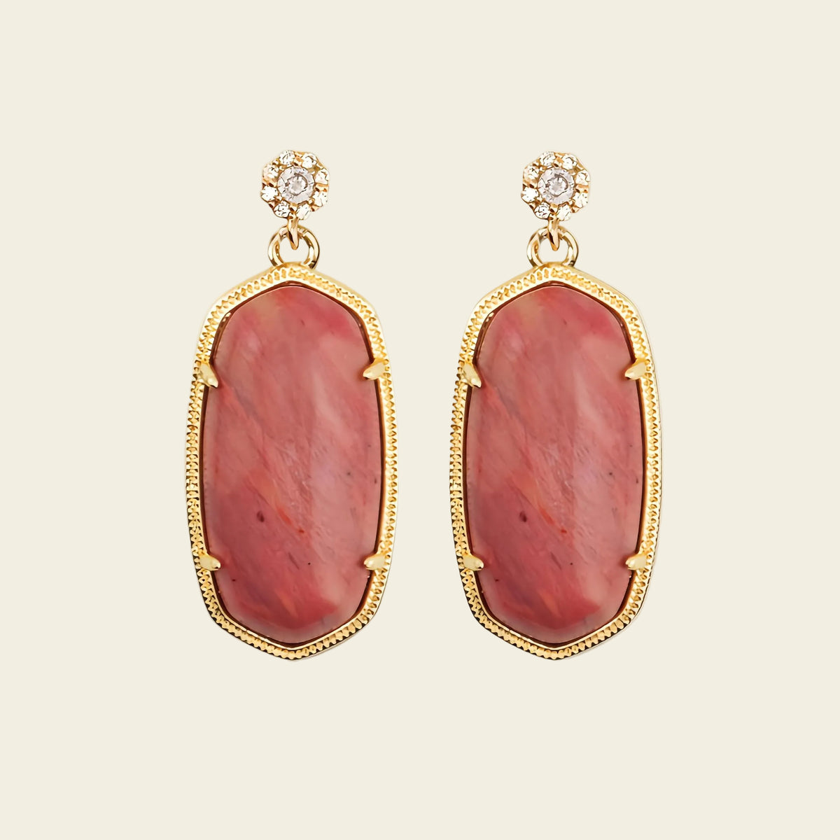 Pair of earrings with red stone and gold frame on a beige background