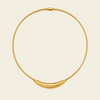 A gold snake-chain necklace with a polished crescent-shaped pendant, displayed on a light cream background.