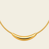 A gold necklace featuring a polished crescent-shaped pendant suspended from a textured snake chain, set against a solid cream background.