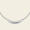 A silver crescent moon pendant necklace on a matching snake chain, displayed against a solid pale peach background.
