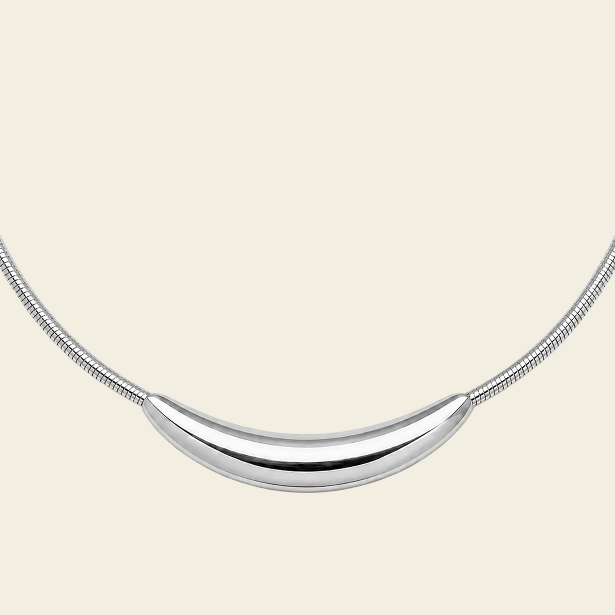 A silver crescent moon pendant necklace on a matching snake chain, displayed against a solid pale peach background.