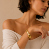 Woman wearing a gold bracelet on a beige background