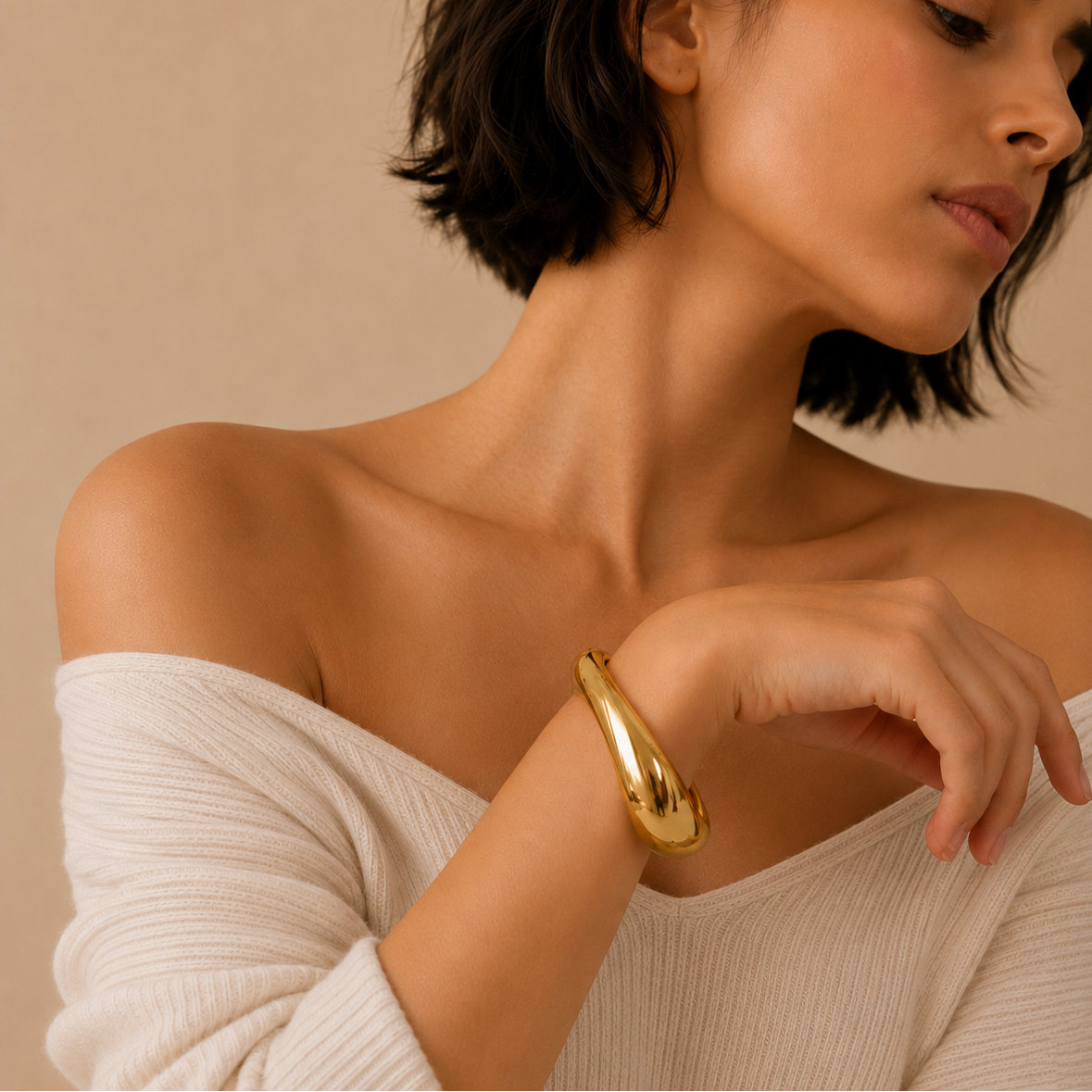 Woman wearing a gold bracelet on a beige background