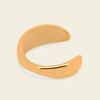 A polished open cuff bangle in a warm gold tone, photographed on a clean off-white background.