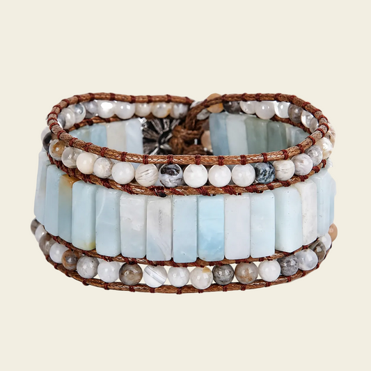 Stack of beaded bracelets with blue, white, and brown beads on a beige background