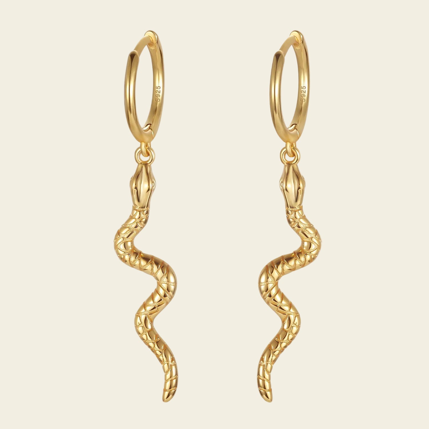 Gold hoop earrings with snake-like designs on a beige background