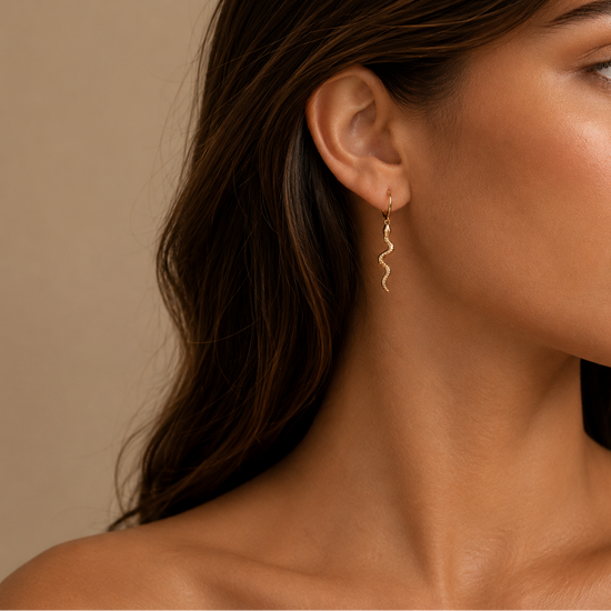Close-up of a woman wearing gold earrings with a neutral background