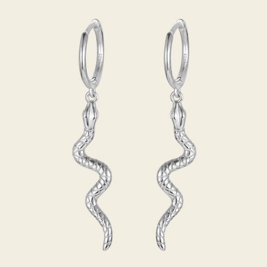 Silver hoop earrings with wavy designs on a light beige background