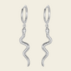 Silver hoop earrings with wavy designs on a light beige background