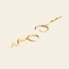 Gold snake-shaped earrings on a beige background