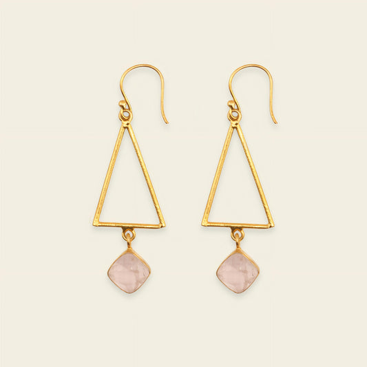 Gold triangle earrings with pink stone drops on a beige background